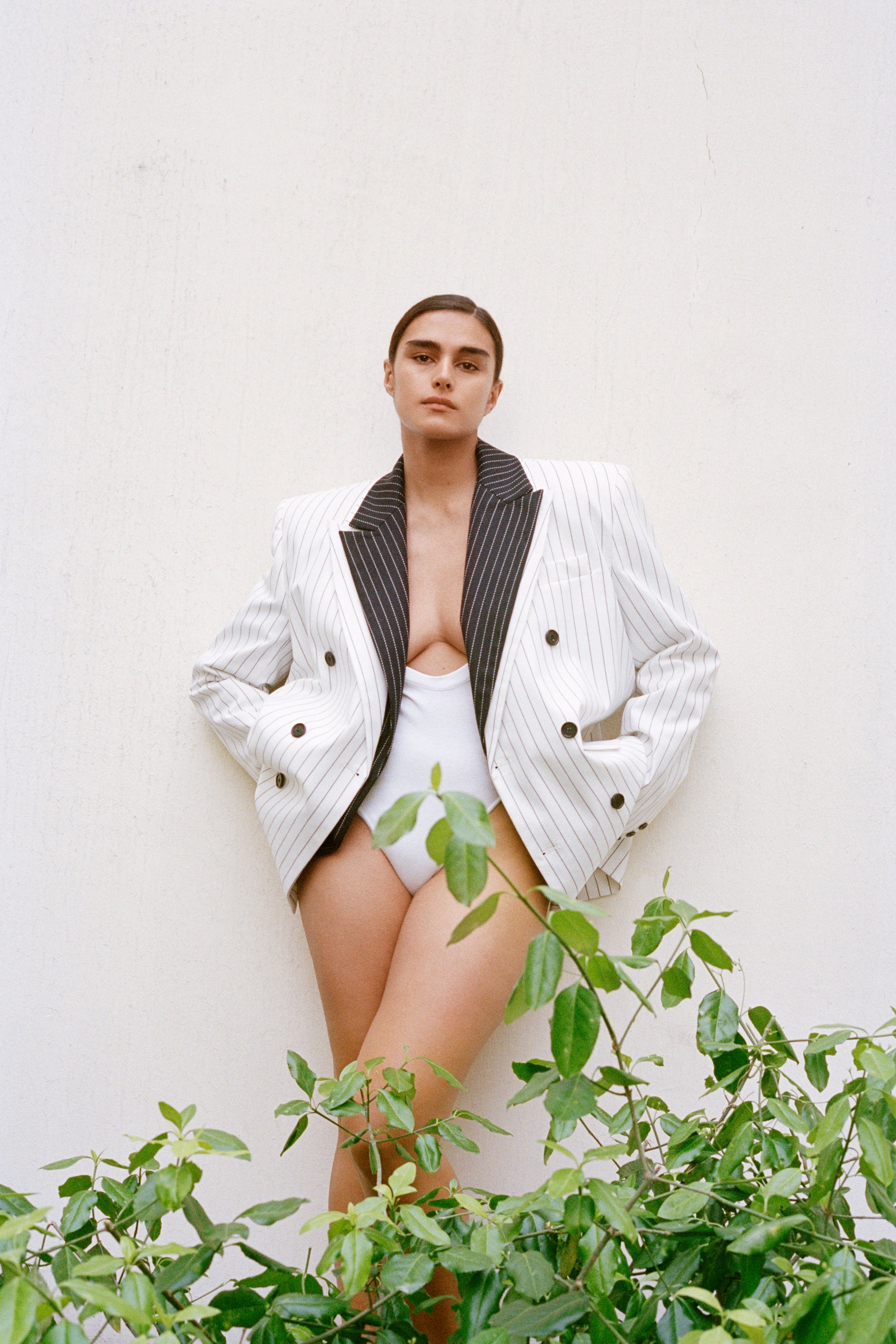 Model Jill Kortleve photographed by Letty Schmiterlow outside wearing a white pinstriped suit jacket and a white swimsuit. 