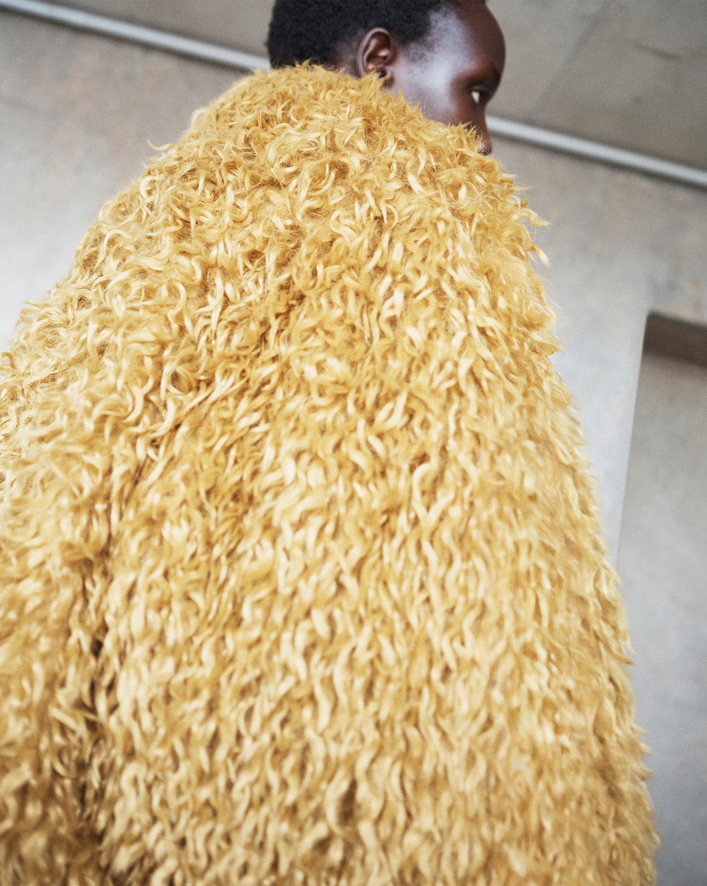 The Frankie Shop model wearing oversized shaggy fur coat in mustard 