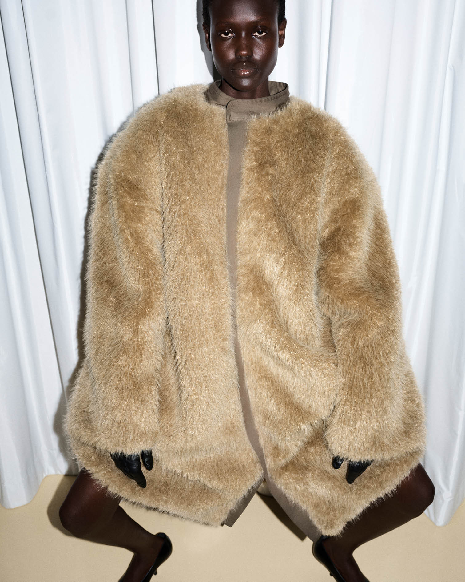 Model wearing a reversible shaggy fur coat in a beige color 